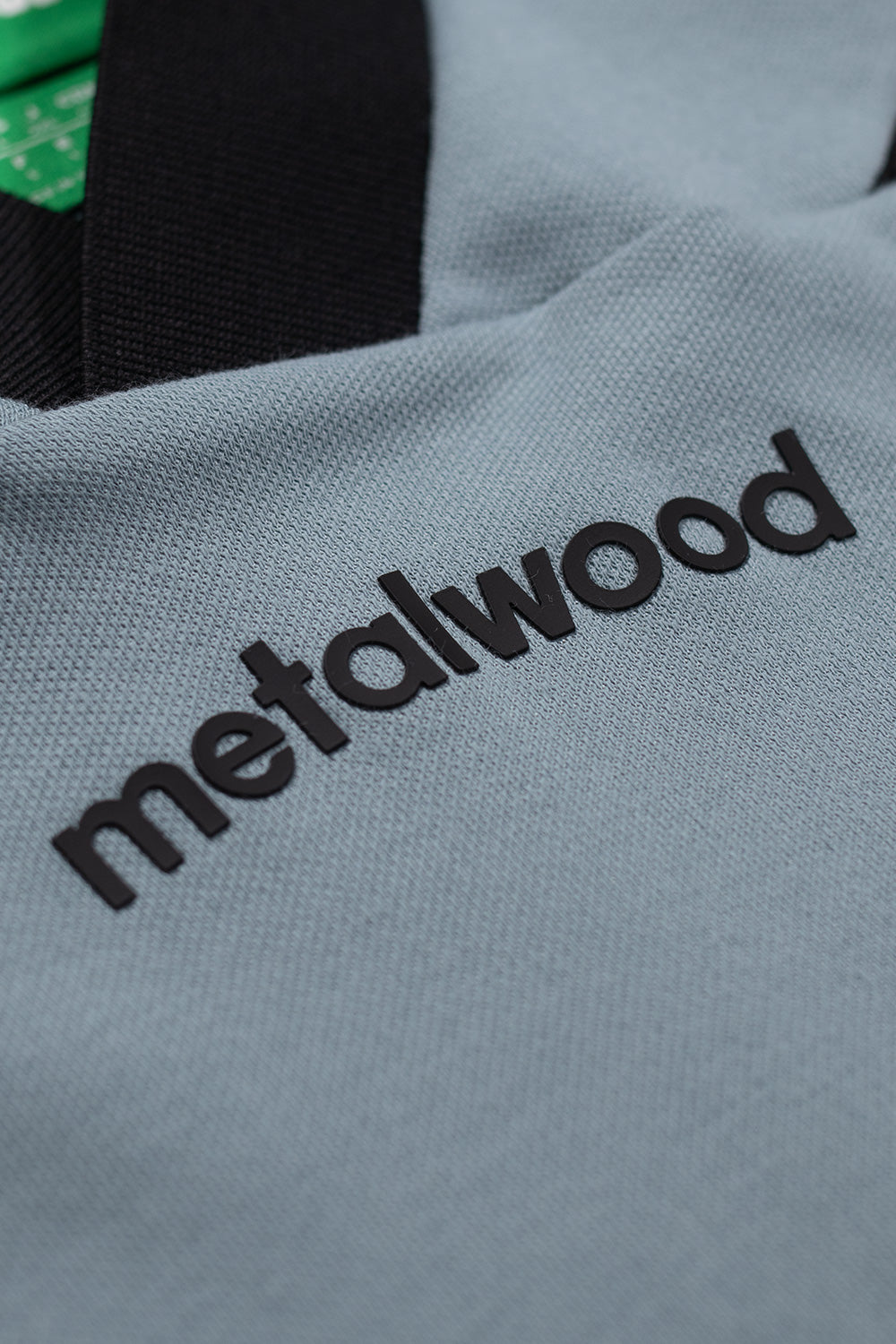 Detailed view of Metalwood logo on adidas x Metalwood Green Earth polo shirt highlighting modern golf streetwear design, smooth cotton blend texture and clean Y2K-inspired aesthetics