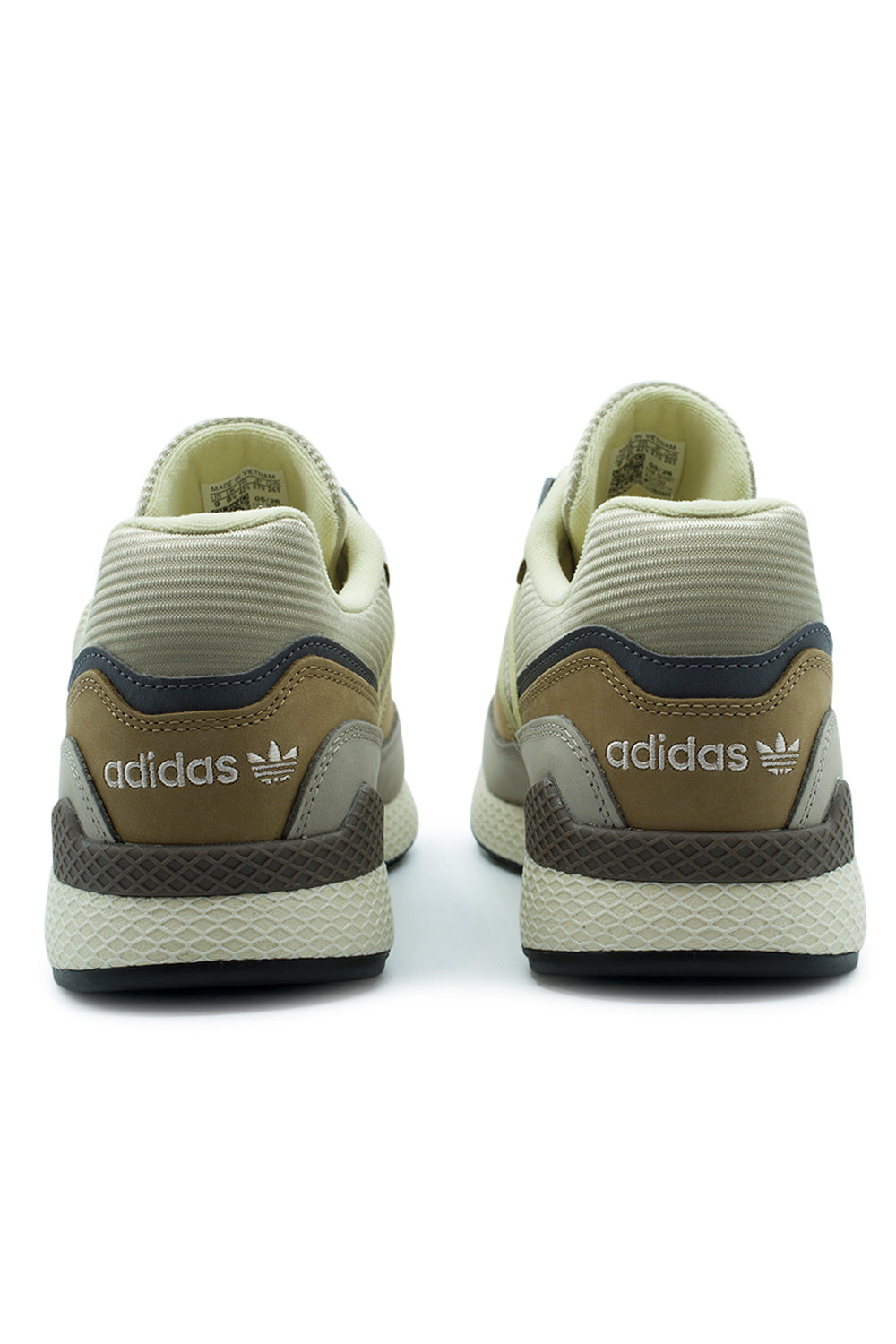 Rear perspective shot of the heels on the Adidas Oregon Ultra Tech sneakers, showing the tan nubuck heel counters with white embroidered Adidas Trefoil lettering, deep charcoal external TPU heel support stabilizer clips, padded cream textile collar lining, and the geometric Dellinger web midsole pattern