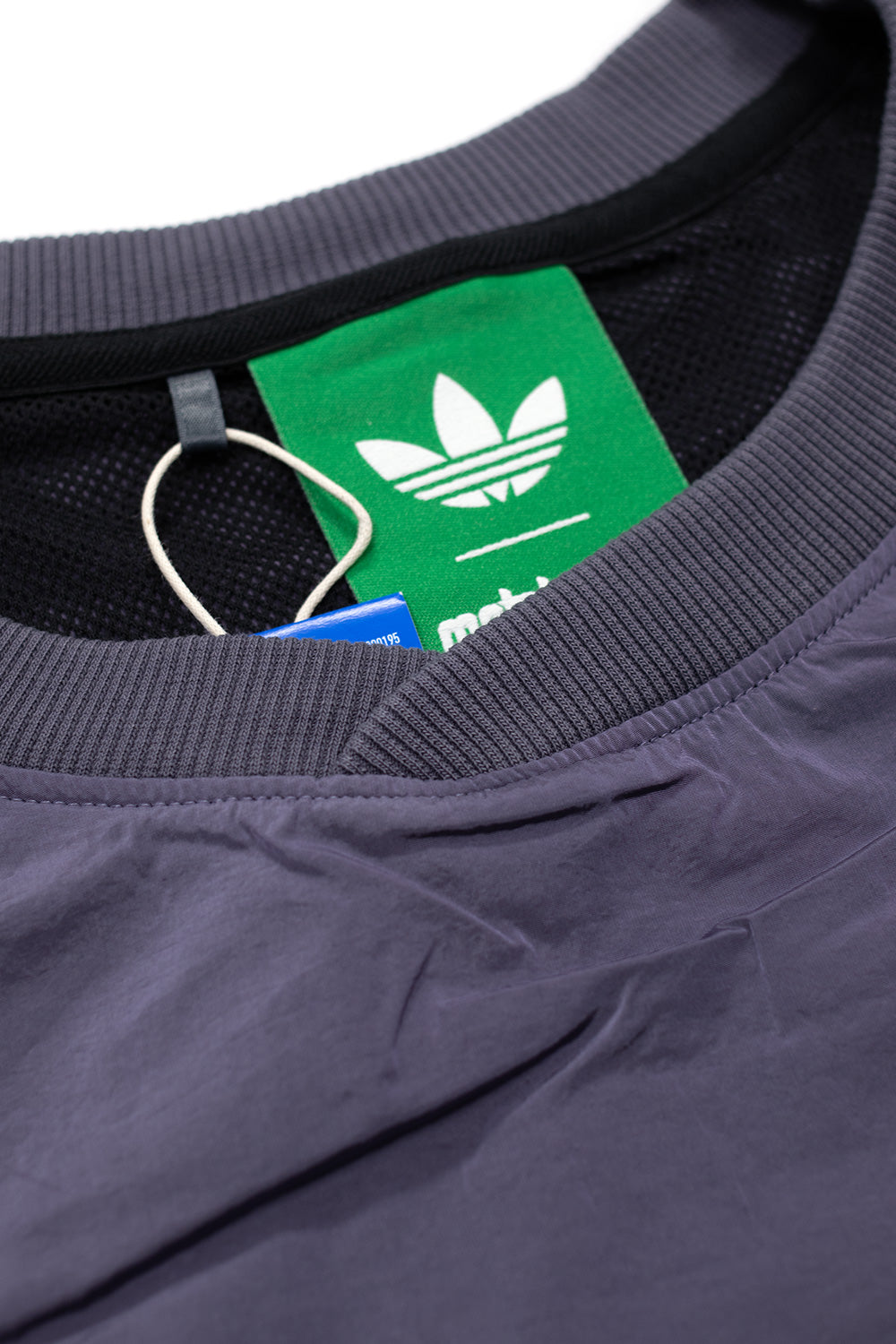 Close-up of ribbed collar and inner label on Adidas x Metalwood pullover showing premium construction, mesh lining, and authentic collaborative branding.