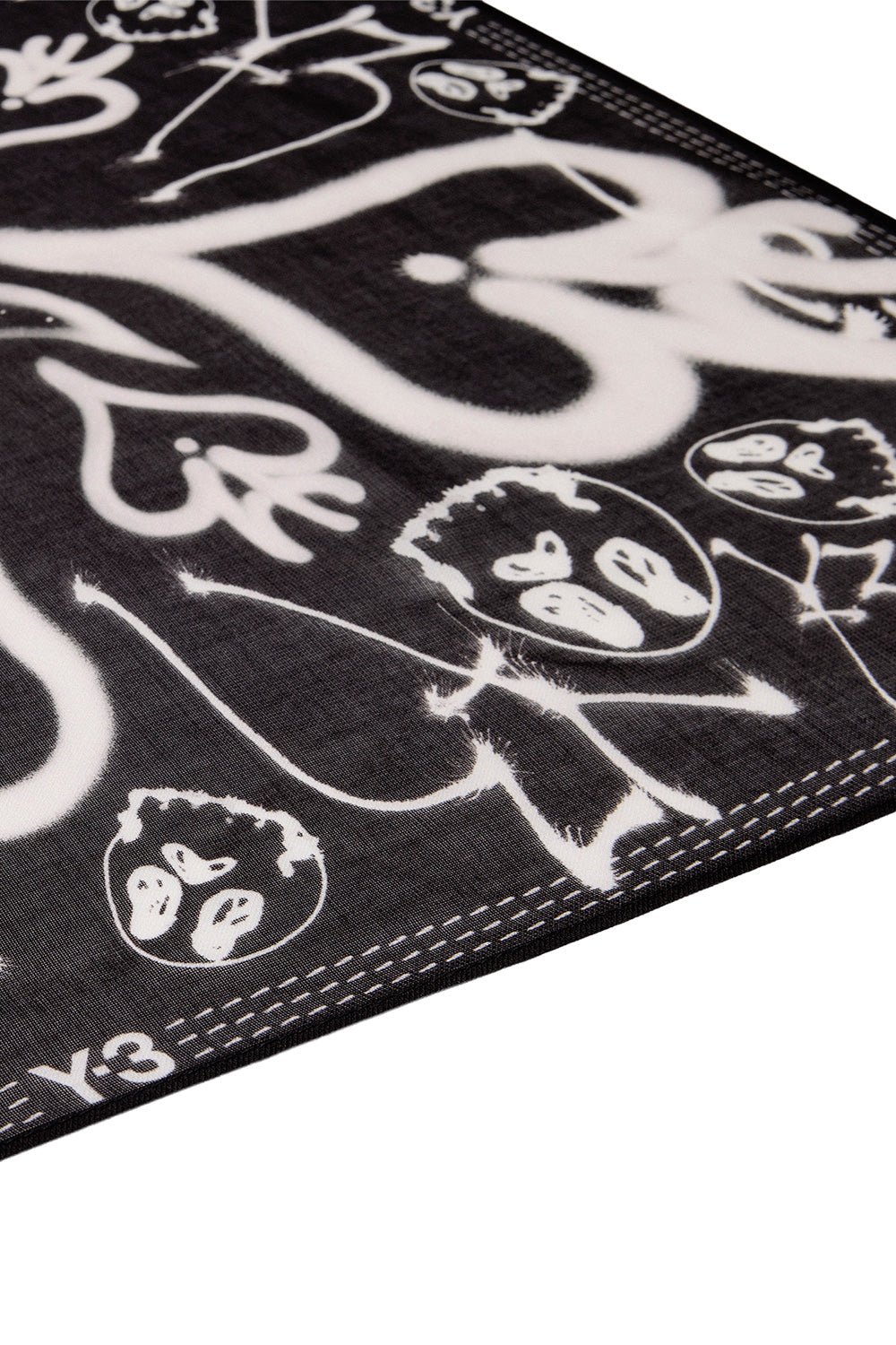 Angled perspective detail view of the black Adidas Y-3 X Chito bandana scarf, highlighting the high-resolution airbrushed spray paint stencil skulls, blurred heart emblems, and white printed Y-3 logo along the outer stitched border.