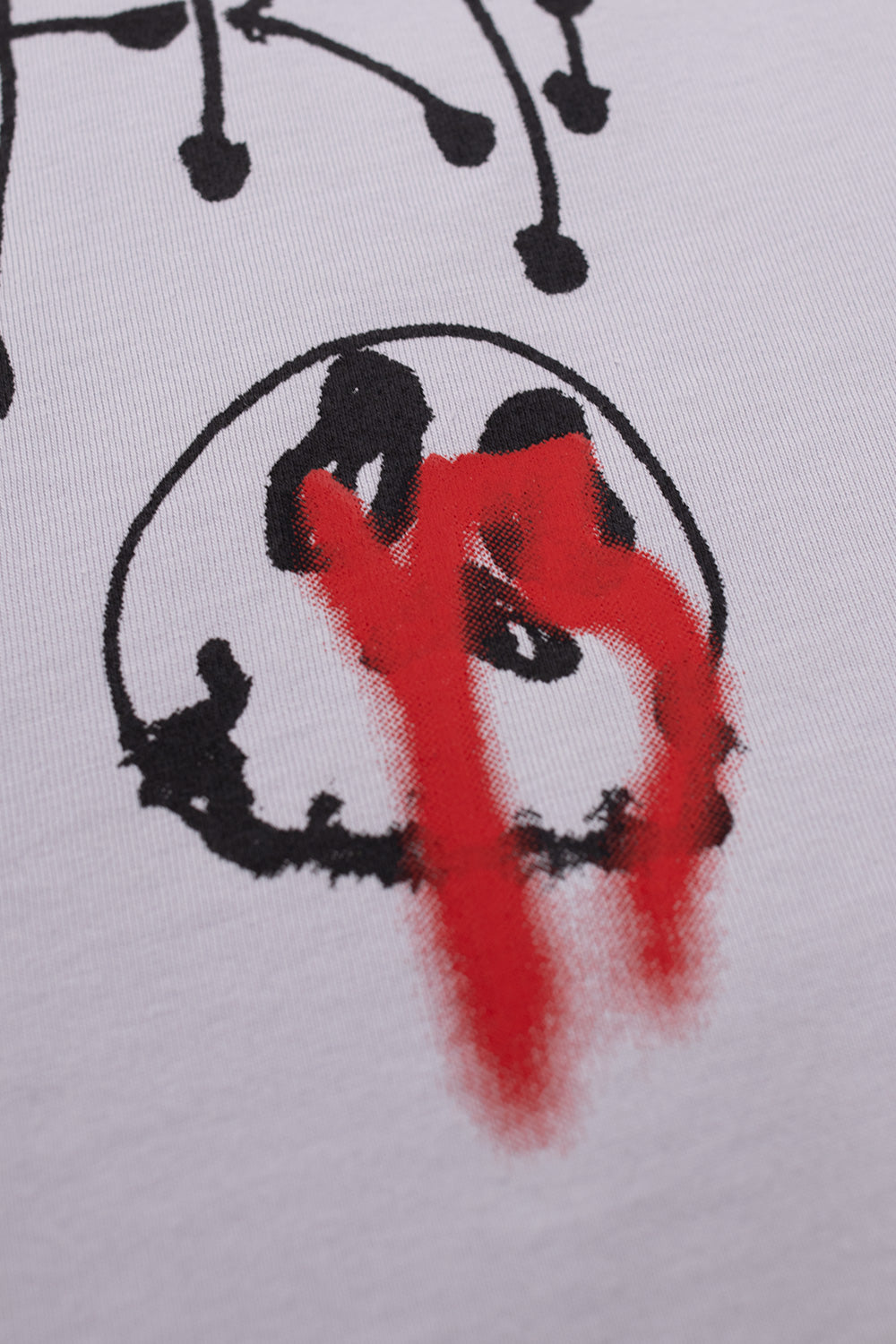 Macro detail shot of the black outlined smiley face with vibrant red airbrush spray paint print on the Adidas Y-3 x Chito City Graphic cotton jersey T-shirt.