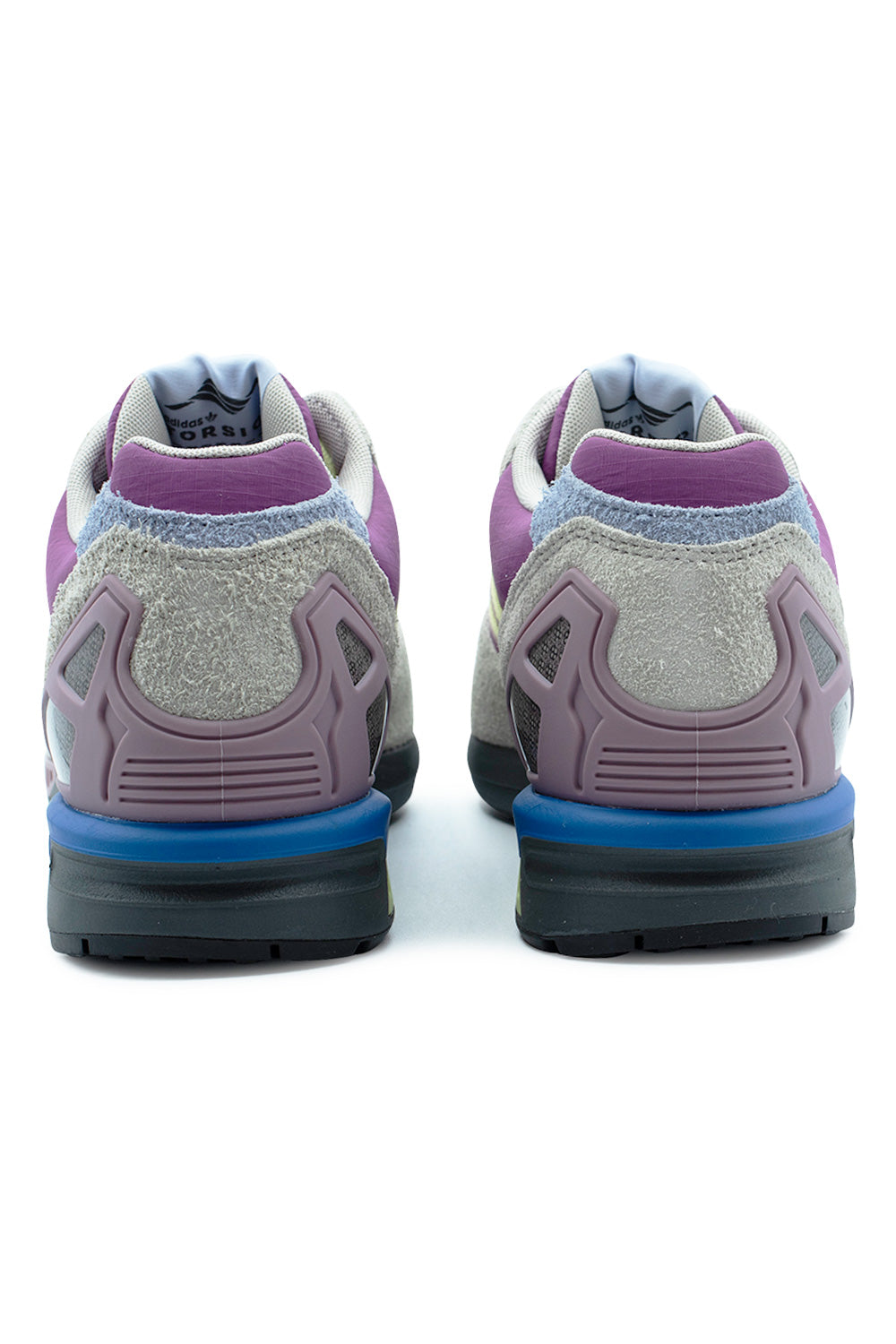 Rear view of the heels of the Adidas ZX 8000 sneakers, displaying the structured semi-translucent purple TPU external heel support cages over mesh underlays, shaggy grey suede heel counters, light purple nylon collars, and bright blue EVA midsole blocks.