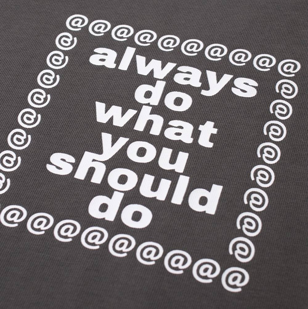 Macro studio close-up of the lower back print on the Always Waza Panelled T-Shirt, showing the crisp white typography reading "always do what you should do" enclosed inside a square border composed of white "@" symbols printed on dark grey heavy cotton fabric.