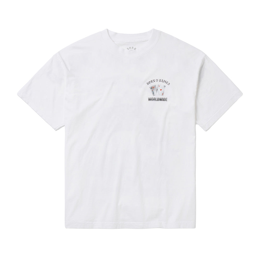 Front flat lay studio perspective of the white Born X Raised Two Pair T-Shirt, displaying a ribbed crewneck collar with printed inner neck branding, clean short sleeves, and a subtle left chest graphic featuring fanned playing cards showing aces and kings set between arched Old English "BORN-X-RAISED" text and "WORLDWIDE" block lettering.