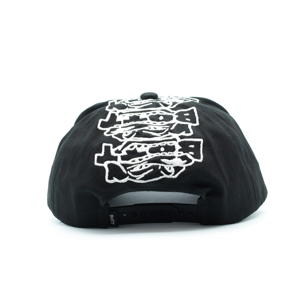 Rear studio perspective of the black BoTT Bottweiler 6 Panel Cap, displaying the adjustable black plastic snapback closure, a woven black "BoTT" brand flag label on the left edge, and the continued white outline embroidery of the stacked cartoon dogs running down the back panels.