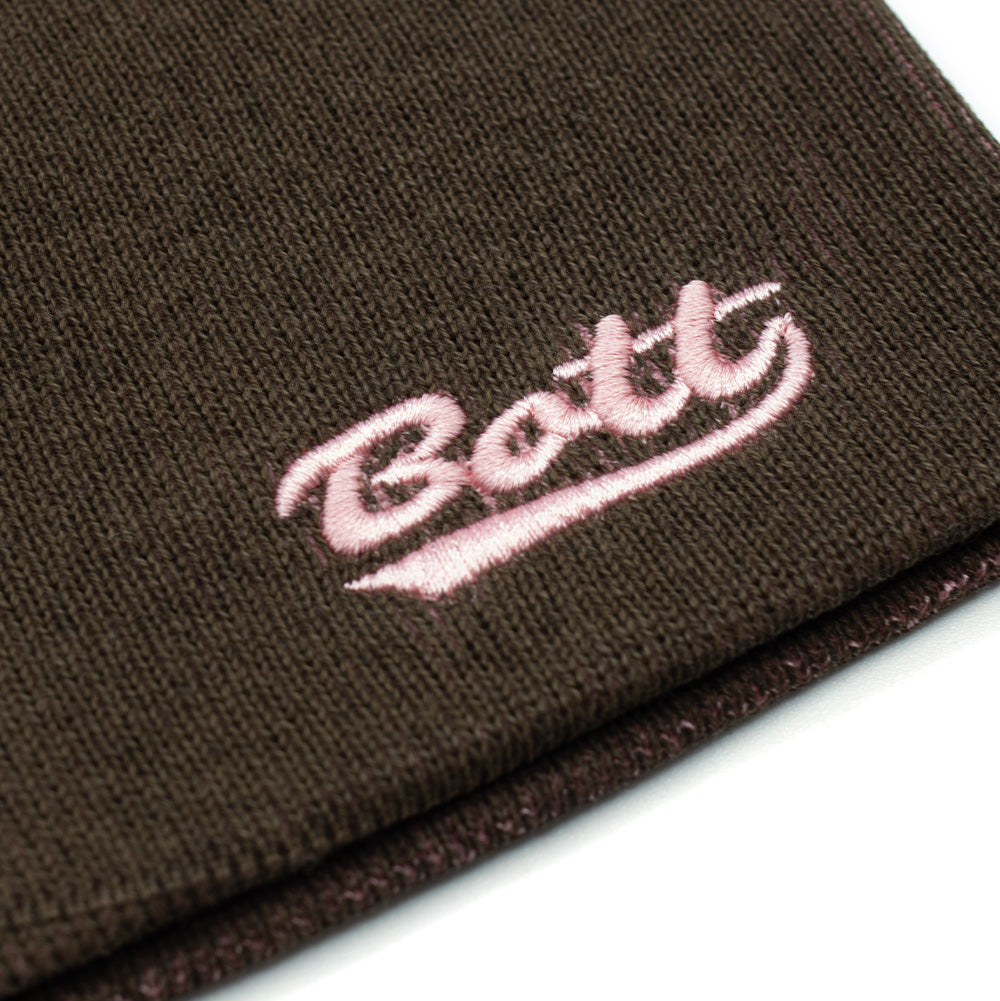 Macro studio close-up of the lower rim on the BoTT Overprint Skullcap Beanie in Brown, detailing the soft, elasticated knit fabric weave and high-density light pink thread embroidery forming the underlined retro varsity-style cursive "BoTT" brand script.