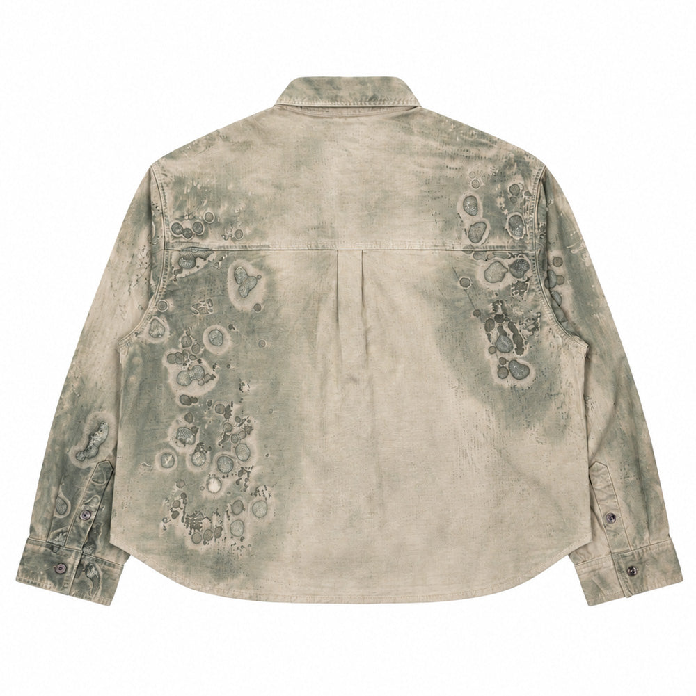 Back flat lay studio perspective of the Brain Dead Cotton Ripstop Cropped Shirt Jacket in Algae, highlighting the straight back yoke with a central knife pleat for added movement, buttoned barrel cuffs, curved tail hem, and organic splash-like circular algae prints dispersed across the sand-and-sage green textured cotton fabric.
