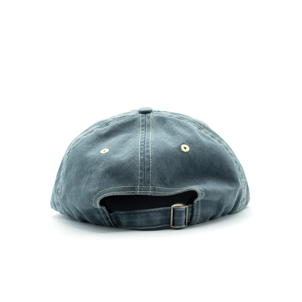 Rear studio perspective of the slate blue By Parra Lowercase Script Logo 6 Panel Hat, highlighting the self-fabric cotton strapback closure with antique-brass metal slider buckle, embroidered ventilation eyelets, and durable contrast seam construction.