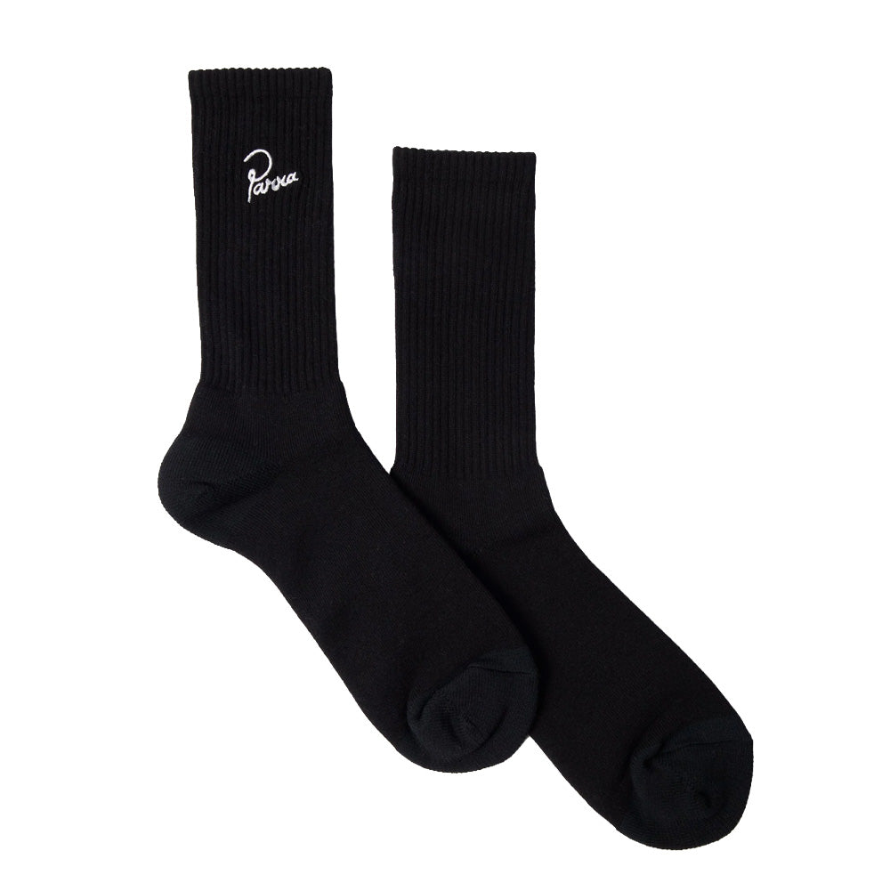 Studio flat lay display of a pair of By Parra Signature Crew Socks in solid jet black, showcasing the premium mid-calf ribbed knit leg with elasticated arch support and smooth reinforced heel and toe construction, crafted in Japan from a soft cotton-blend yarn and accented with crisp white cursive "Parra" script embroidery positioned neatly on the outer upper ribbed cuff.