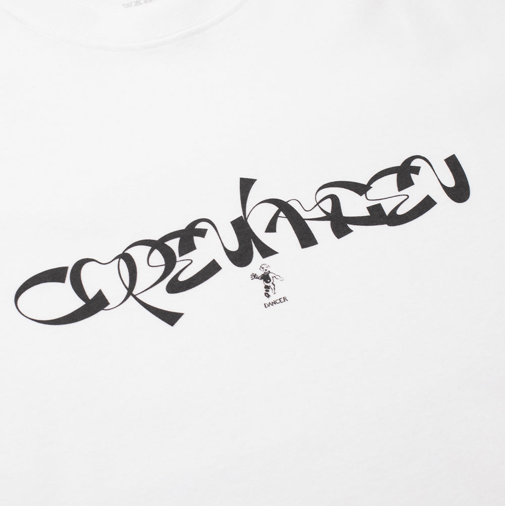 Angled studio close-up of the front chest graphic on the white Dancer Copenhagen T-Shirt, displaying the crisp black screen-printed flowing cursive ribbon lettering with the miniature dancing cherub mascot and "DANCER" uppercase text placed directly below on pure white cotton jersey fabric.