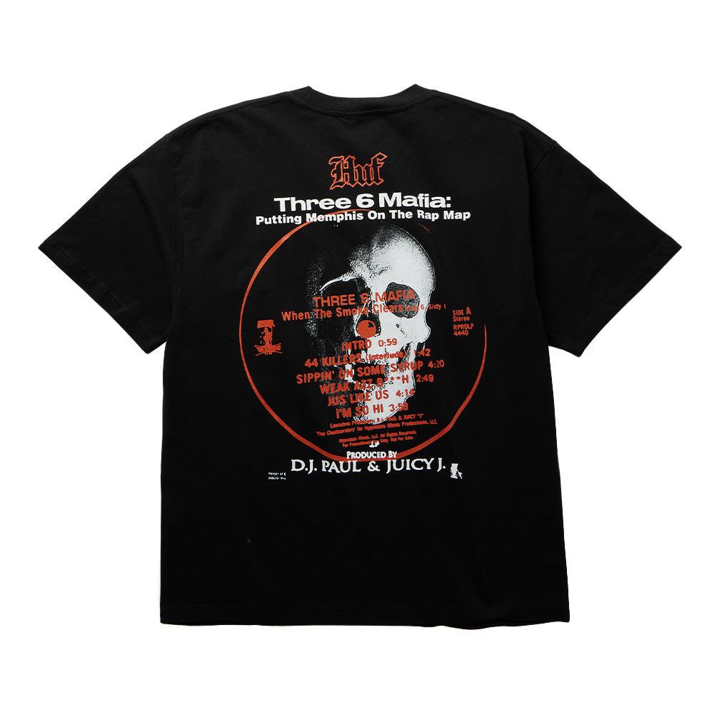 Back flat lay view of the black Huf X Three 6 Mafia Mystic Styles T-Shirt, displaying an oversized circular vinyl record graphic centered around a skull album art motif, the tracklist for "When The Smoke Clears" including "Sippin' On Some Syrup", topped with Gothic HUF lettering and "Three 6 Mafia: Putting Memphis On The Rap Map", finished with production credits at the hem.