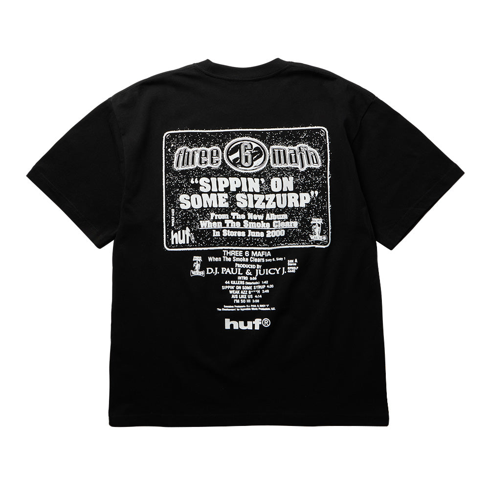 Back flat lay view of the black Huf X Three 6 Mafia Sizzurp T-Shirt, showcasing a retro white-and-black promotional poster print for the Memphis rap single "SIPPIN' ON SOME SIZZURP" from the album When The Smoke Clears, complete with Three 6 Mafia disc branding, production credits for DJ Paul & Juicy J, tracklist snippets, and a bold white lowercase "huf®" logo at the lower back.