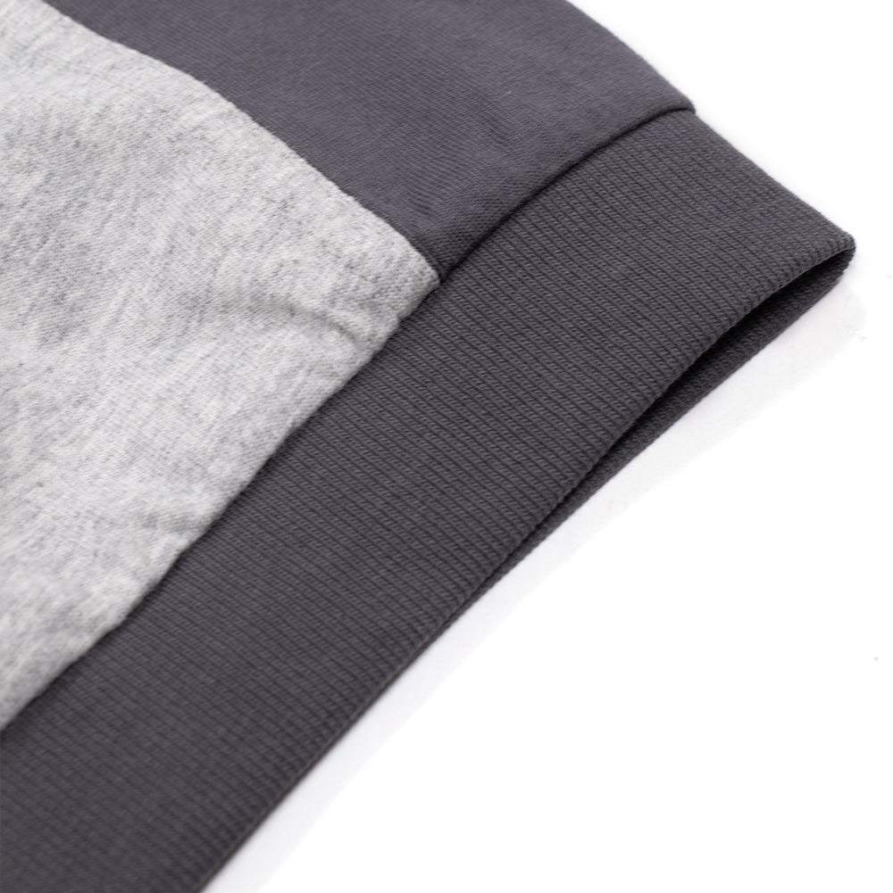 Macro studio close-up of the sleeve cuff on the Metalwood Studio Creature T-Shirt, focusing on the fine-ribbed charcoal knit cuff band cleanly stitched to the two-tone sleeve featuring melange heather grey and solid dark grey panel construction.
