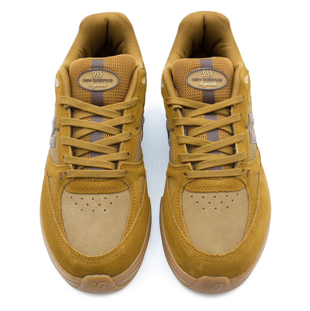 Top-down studio view of the New Balance Numeric Andrew Reynolds 933 skate shoes, highlighting the perforated tan leather toe boxes, golden suede toe caps, tonal flat cotton laces over breathable mesh tongues, and custom oval rubberized tongue badges displaying 933 New Balance Reynolds branding.