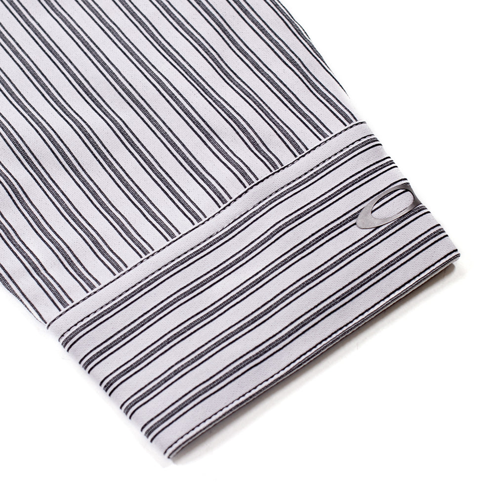 Macro studio close-up of the sleeve cuff on the Oakley FGL Fuel LS Shirt 6.7 in White, detailing the horizontal stripe construction of the structured cuff band accented by a heat-transferred metallic silver Oakley Ellipse logo near the outer edge.