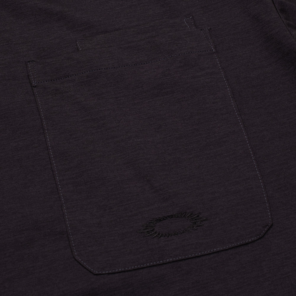 Macro studio view of the chest pocket detailing on the Oakley FGL Scratch SS Tee in Phantom, showcasing the double-needle top hem with integrated tool compartment and subtle tonal black embroidery forming the jagged, soundwave-style scratch outline of the Oakley Ellipse emblem.