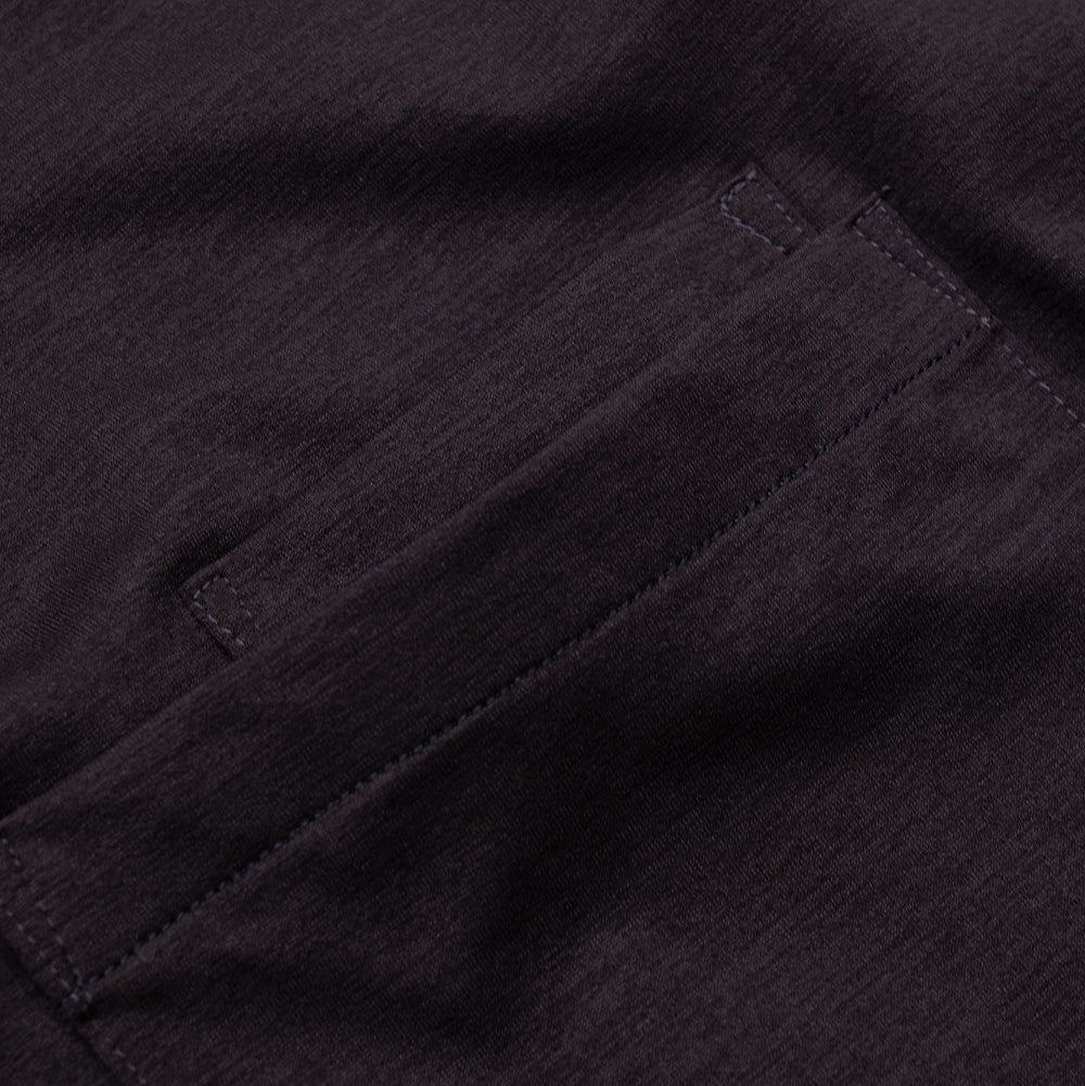 Detailed macro perspective of the upper pocket rim on the Phantom Oakley FGL Scratch Tee, highlighting the heavy bartack corner reinforcement stitching, durable layered seam construction, and the fine-gauge heathered charcoal performance fabric weave.