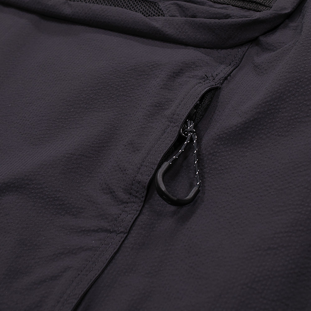 Macro close-up shot of the lower hand pocket opening on the Oakley FGL Stroke Anorak, detailing the concealed vertical zipper track, reinforced bartack seam finishing, and a black reflective-flecked paracord zipper pull loop fitted with a contoured rubberized finger grip.