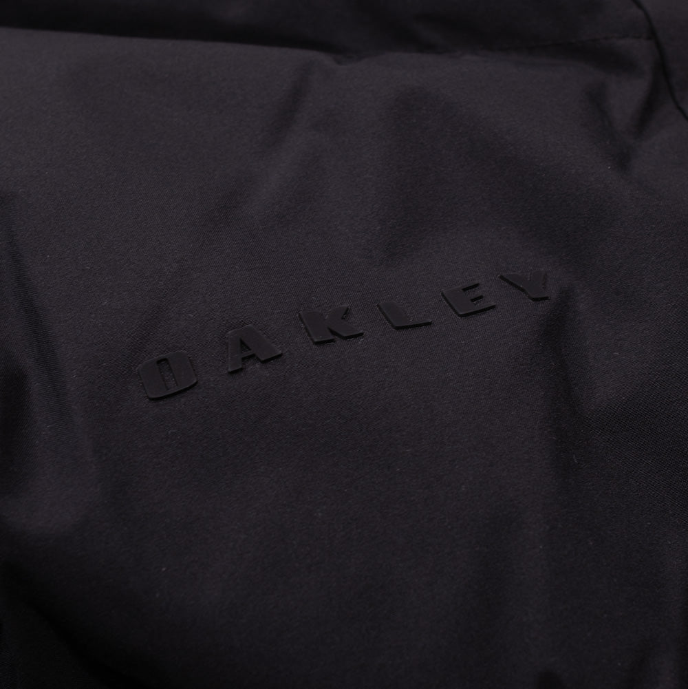 Studio macro shot of the tonal Oakley wordmark branding on the Retrofuel Gore-Tex Down Jacket, featuring clean matte black uppercase "OAKLEY" lettering seamlessly embossed onto the technical matte fabric.