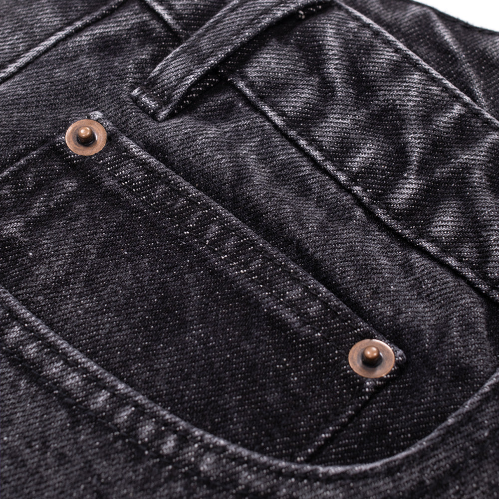 Macro studio close-up of the front right coin pocket on the Token Alphabet Jeans, detailing the washed charcoal denim twill grain, heavy tonal seam stitching, and aged copper metal reinforcement rivets on the pocket lip.
