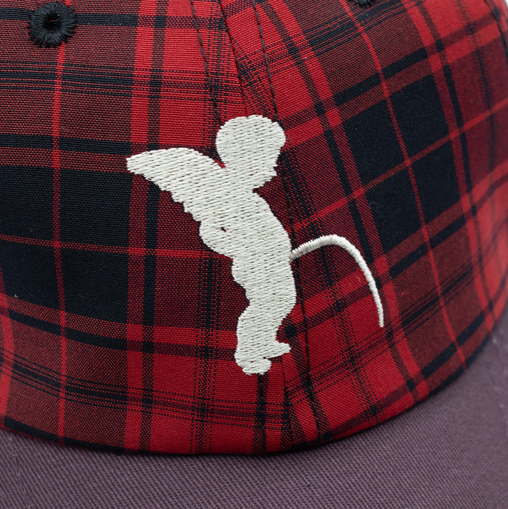 Macro studio close-up of the front panel on the Token Pissing Angel Cap, highlighting the dense off-white embroidery depicting the iconic winged Manneken Pis cherub statue, set against the woven red, black, and navy blue twill plaid check pattern.