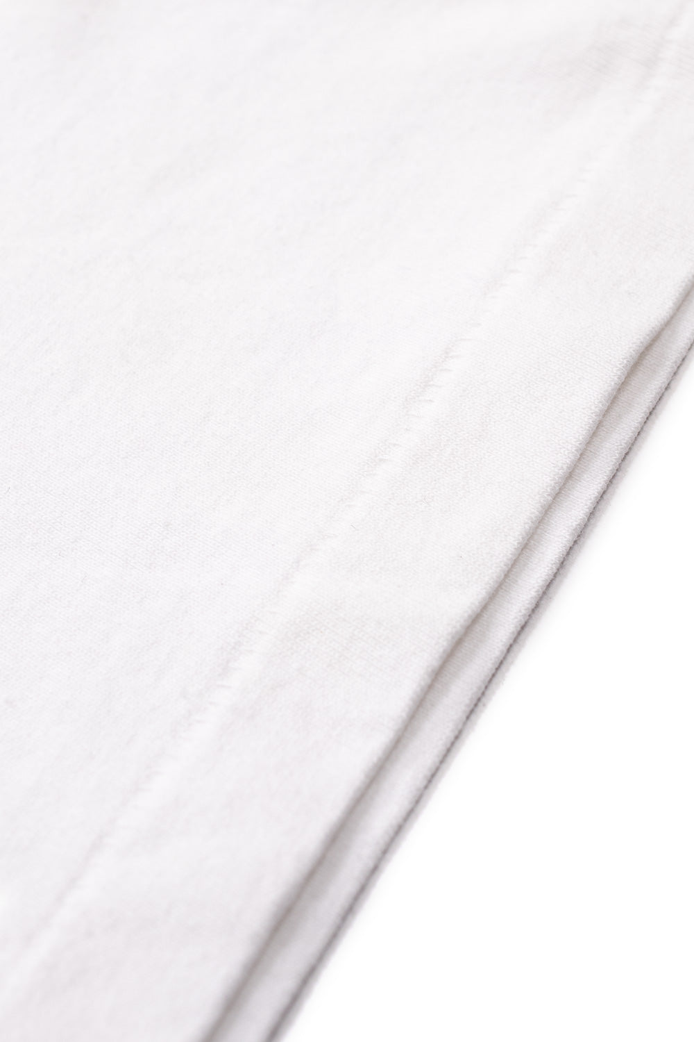 Detailed shot of the vintage single-stitch hem on the white Wacko Maria washed heavy weight cotton t-shirt made in Japan.