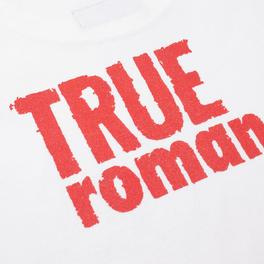 Macro perspective of the upper back graphic print on the Wacko Maria x True Romance T-Shirt, detailing the textured red screen-printed ink with weathered stencil edges spelling out the stacked "TRUE ROMANCE" movie logo on smooth white heavyweight cotton.