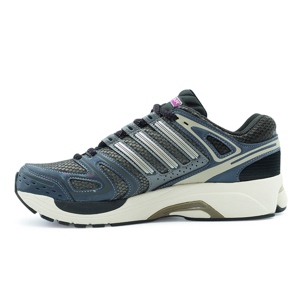 Medial profile studio view of the adidas Adistar Control 5, focusing on the arched arch support, khaki synthetic midfoot underlays, silver Three Stripes cage, ventilated medial quarter panels, and the integrated olive-toned Torsion System shank along the cream midsole.