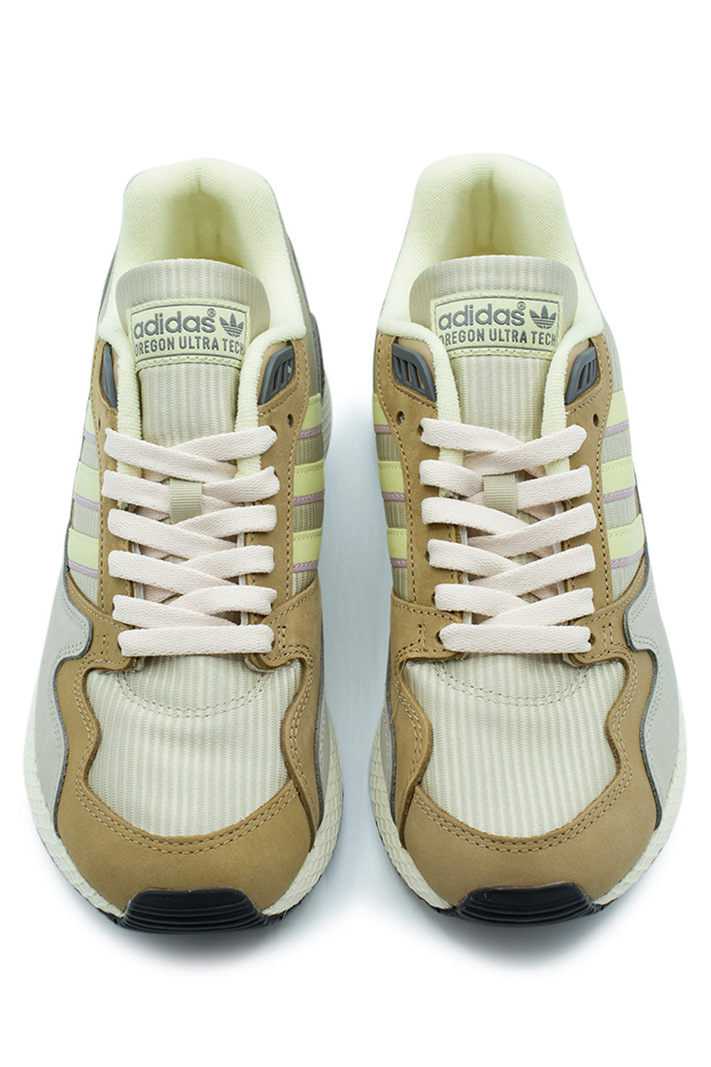 Top-down studio shot of a pair of Adidas Oregon Ultra Tech running shoes, displaying the fine-cord ribbed mesh toe boxes, tan nubuck mudguards, off-white flat cotton laces through molded grey TPU eyelet inserts, and ribbed textile tongues with printed green Adidas Trefoil Oregon Ultra Tech labels