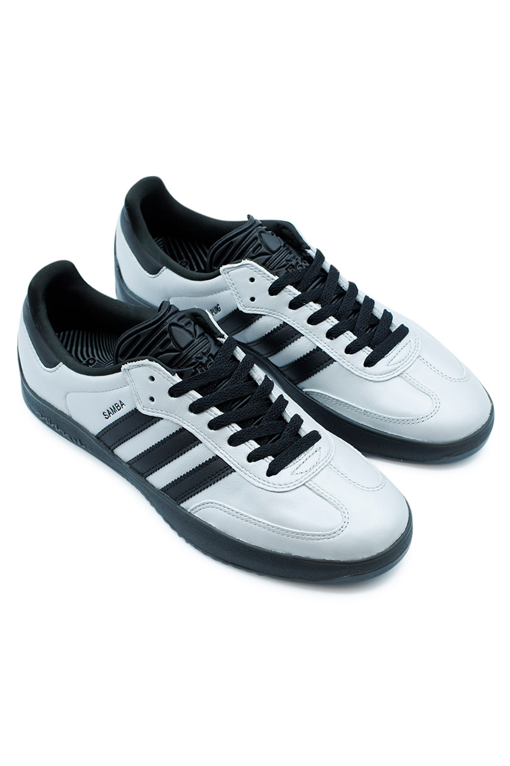 Pair of Adidas Puig Samba Silver Metallic Core Black sneakers angled perspective highlighting leather synthetic upper, flexible build and modern skate performance design