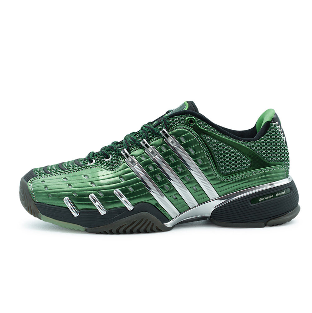Lateral profile studio view of the adidas x Brain Dead Barricade V shoe in Dark Green, Silver Metallic, and Carbon, showcasing the metallic green ribbed synthetic overlays, open-cell mesh base, polished mirror-chrome Three Stripes support cage, sculpted carbon black midsole, and lateral heel "brain dead" branding inset.