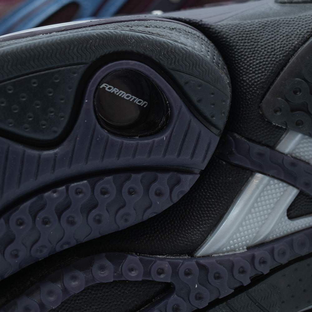 Extreme macro detail of the decoupled lateral heel pod on the Adidas X Hardies Adistar Control 5 outsole, focusing on the embossed circular "FORMOTION" badge, fine grip nubs, and grooved rubber traction channels.
