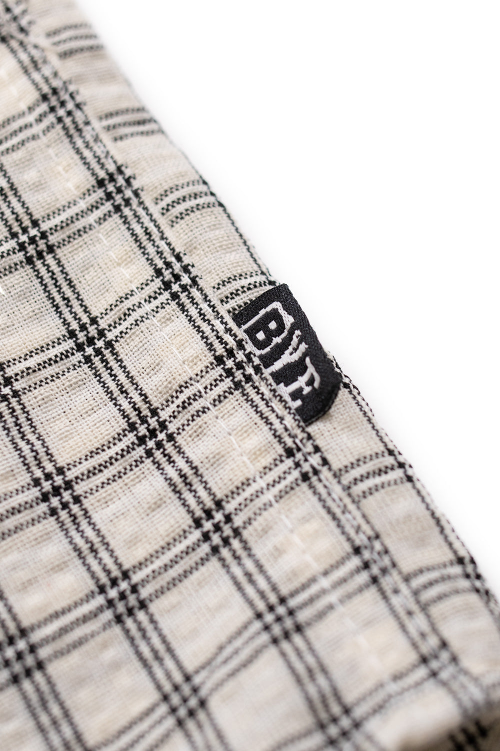 Close-up of Bye Jeremy Supper Button Up Shirt collar showing textured checked cotton fabric and branded blue neck label, highlighting Parisian skatewear craftsmanship.