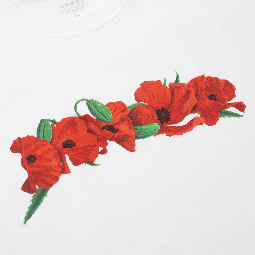 Angled macro studio close-up of the front chest graphic on the Dancer Poppy Flowers T-Shirt, highlighting the rich botanical screen-print details of the bright red open petals, black stamens, and green foliage of the poppy blossoms printed onto smooth white cotton fabric, with printed inner neckline care details faintly visible above.