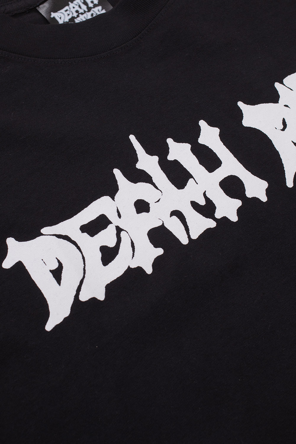 Detailed macro view of the thick rib collar and the white metal-style brand logo text printed on the front of the black Death Rites t-shirt.