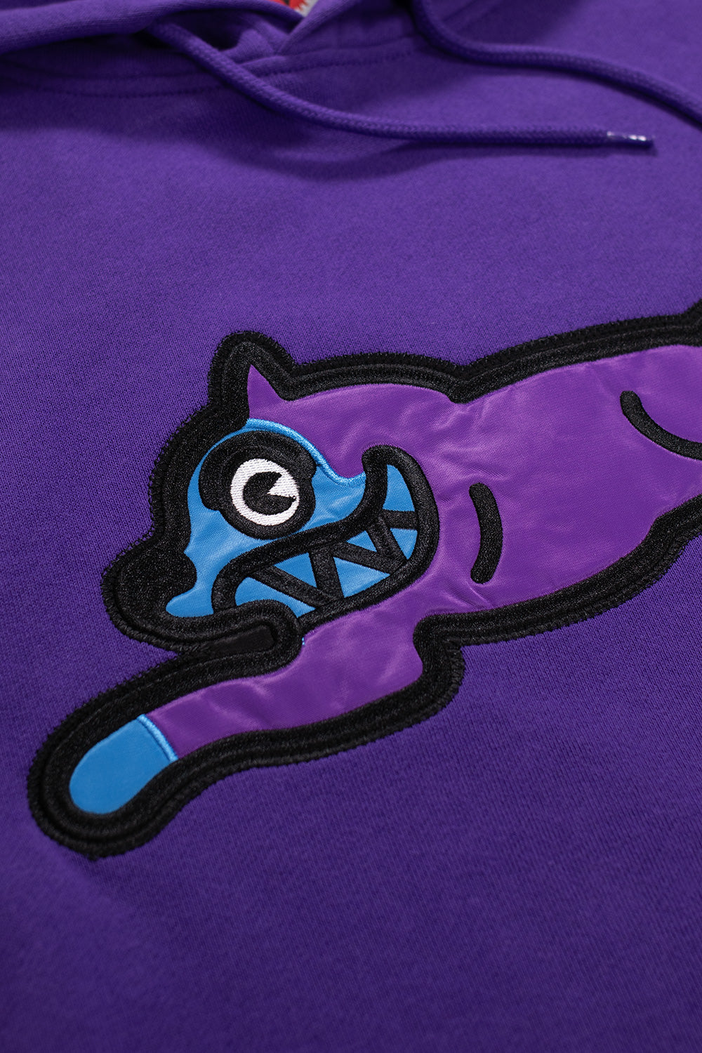 Detailansicht der Running Dog Stickerei auf dem IceCream Popover Hood in Purple – hochwertig verarbeitet mit Satin-Finish.