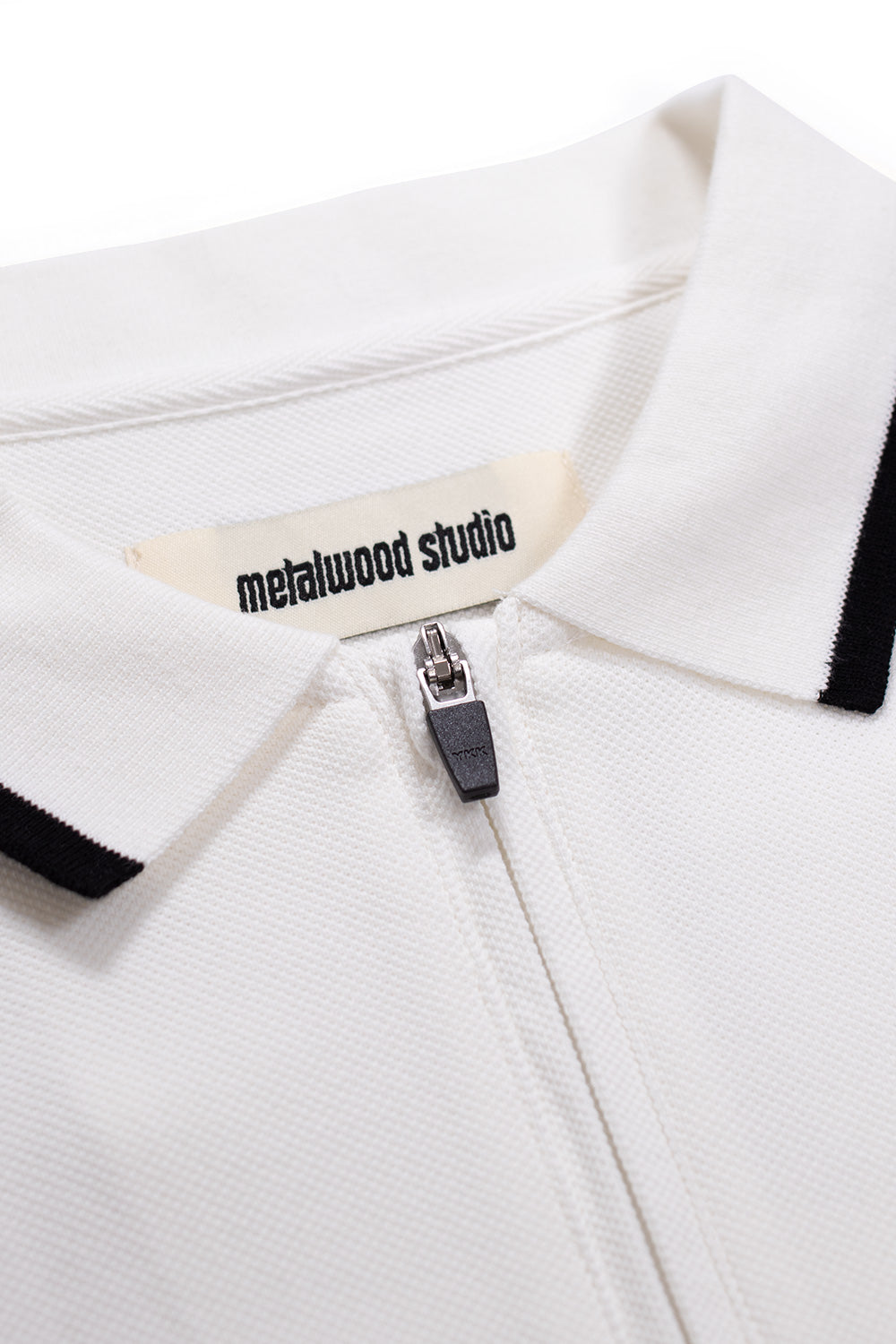 Metalwood Studio World Class Zip Polo White – 1/4-Zip-Design und gesticktes Branding auf der Vorderseite für einen stylischen Retro-Golf-Look.