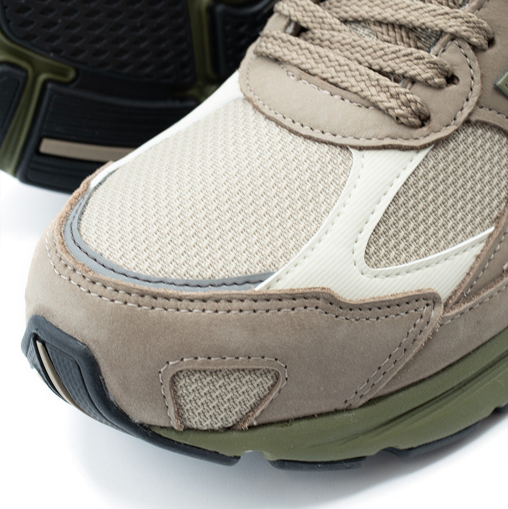 Detailed macro shot of the toe cap and vamp on the New Balance 2010 (GORE-TEX) in Mushroom and Timberwolf, focusing on the fine cross-weave ballistic mesh, cream synthetic overlay trim, curved reflective piping, and double-needle stitching along the front nubuck mudguard.