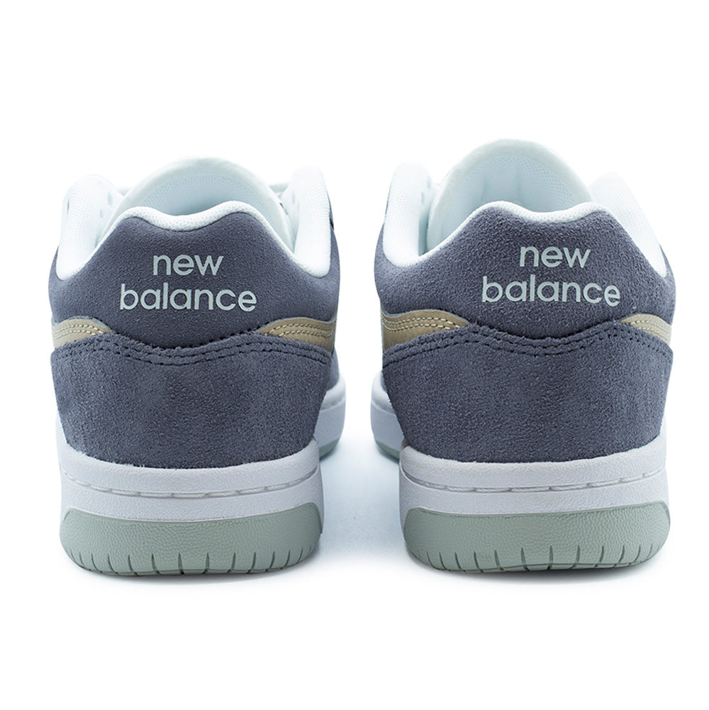 Rear studio perspective of the New Balance Numeric 480 heel construction, highlighting the padded white mesh collar lining, grey-blue suede heel counters with double-needle reinforcement stitching, tan leather collar underlays, white printed "new balance" typography on the heel tabs, and two-tone white and pale green rubber cupsole bases.