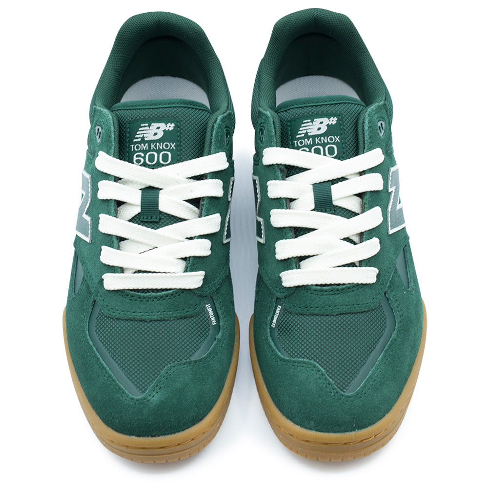 Top-down studio view of the New Balance Numeric Tom Knox 600 pro skate shoes, showing the green mesh toe boxes reinforced with bonded FantomFit overlays, dark green suede mudguards, flat white laces over padded mesh tongues, and woven NB# Tom Knox 600 tongue labels.