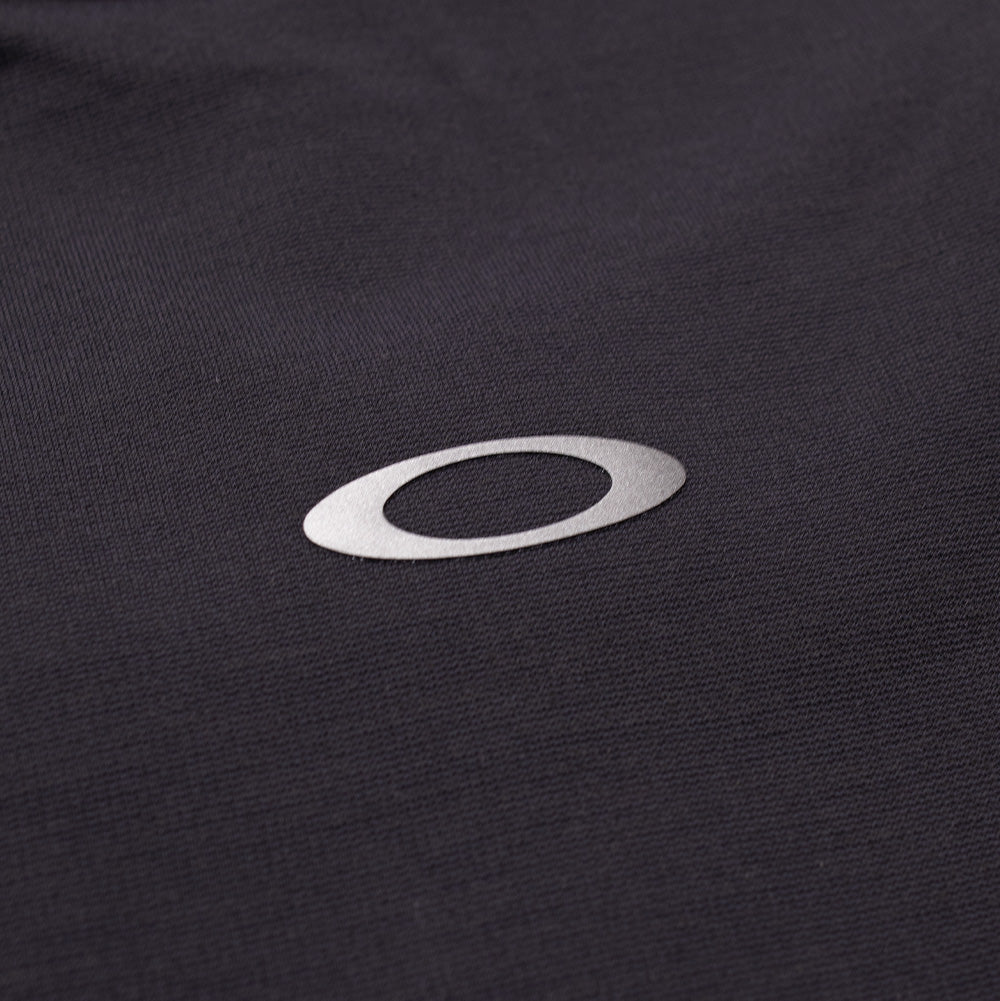 Extreme macro close-up of the rear collar branding on the Oakley FGL Union SS Tee in Phantom, displaying the clean lines of the reflective silver Oakley Ellipse logo cleanly bonded onto the fine-gauge charcoal grey technical textile.