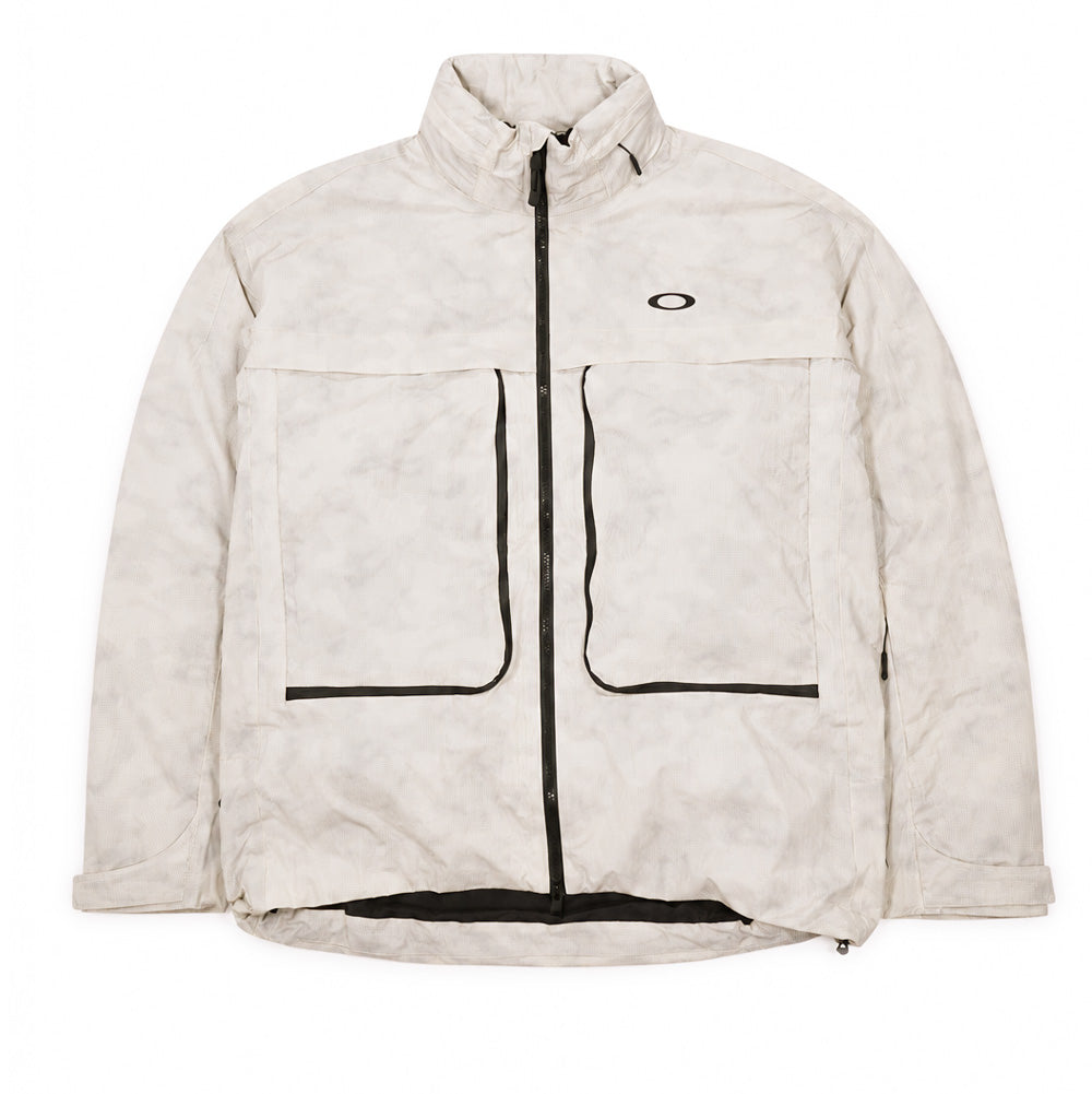 Front flat lay view of the Oakley Mthod Glow Shell Jacket in Reflective Camo Mist with smooth-faced modular chest storm flaps closed, showcasing the minimalist technical aesthetic, clean matte black AquaGuard seam tracks, and small black Oakley Ellipse logo on the left chest.