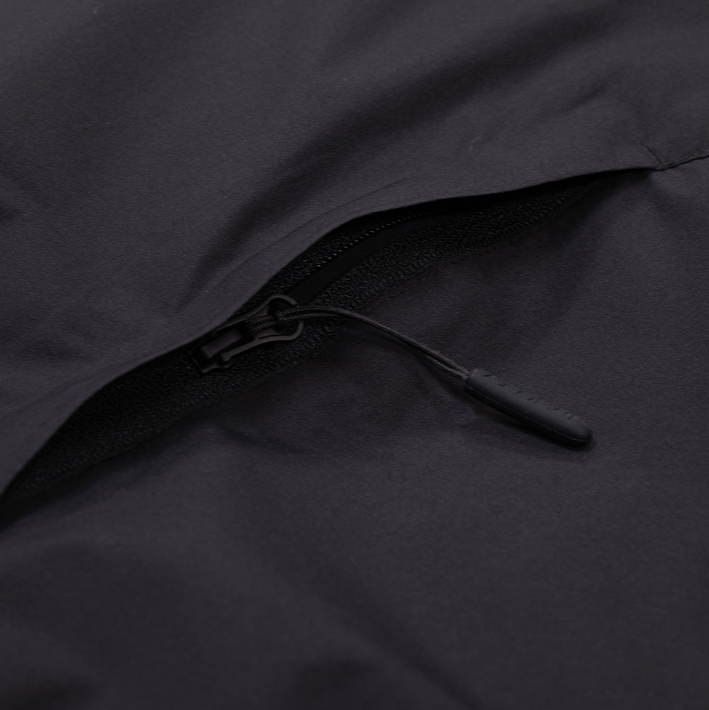 Close-up studio perspective of an exterior pocket closure on the Oakley Retrofuel Gore-Tex Down Jacket, displaying the concealed zipper track sheltered under an angled protective storm welt, complete with a textured black cord puller.