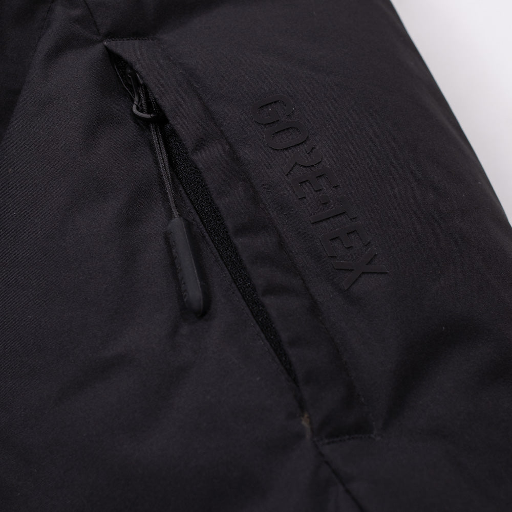 Macro studio view of the sleeve pocket on the Oakley Retrofuel Gore-Tex Down Jacket, highlighting the vertical zippered forearm pass pocket with long pull cord and bold debossed tonal "GORE-TEX" branding pressed directly into the technical shell textile.