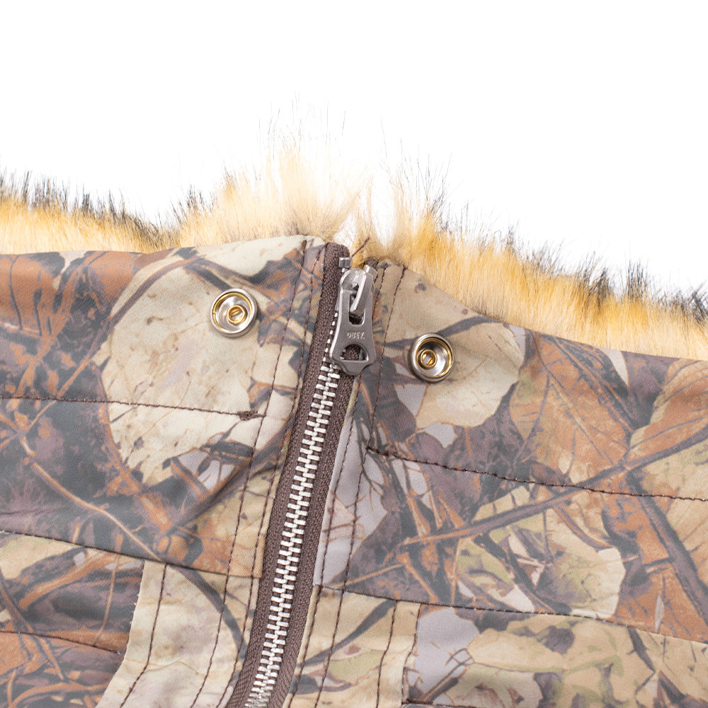 Extreme macro shot of the split hood construction on the Obey N-2B Short Parka, showing the heavy-duty central metal zipper with OBEY puller, dual snap fastenings, and the transition between the quilted camo hood fabric and the fluffy tipped faux-fur trim.
