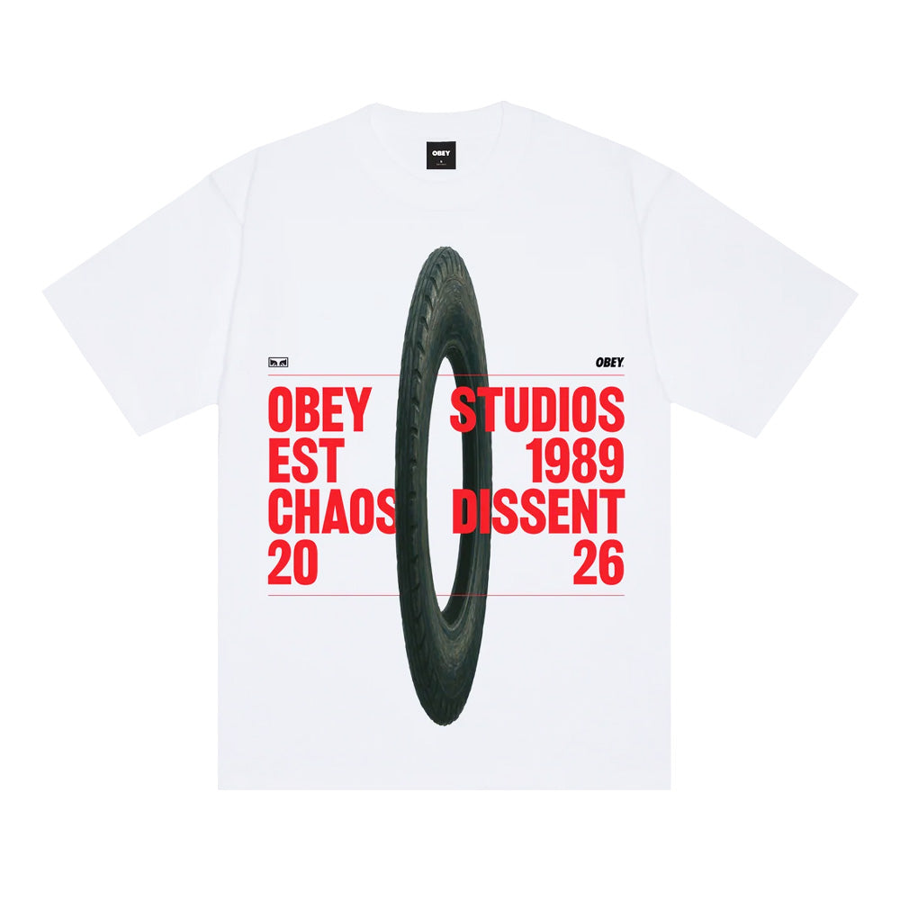 Front flat lay view of the Obey Studios Chaos Dissent Heavyweight T-Shirt in crisp white, cut in a classic boxy streetwear fit with short sleeves and a ribbed crewneck collar, showcasing a large centered graphic print of a vertical motorcycle tire overlaid with bold red block typography reading "OBEY STUDIOS EST 1989 CHAOS DISSENT 2026".