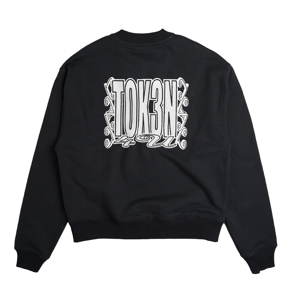 Back flat lay view of the black Token Grand Crewneck sweatshirt, showcasing a boxy relaxed skate fit, ribbed crewneck, dropped shoulders, and a large white screen-printed graphic of the stylized uppercase "TOKEN" logo encircled by intricate ornate baroque filigree swirls and flourishing accents centered on the back.