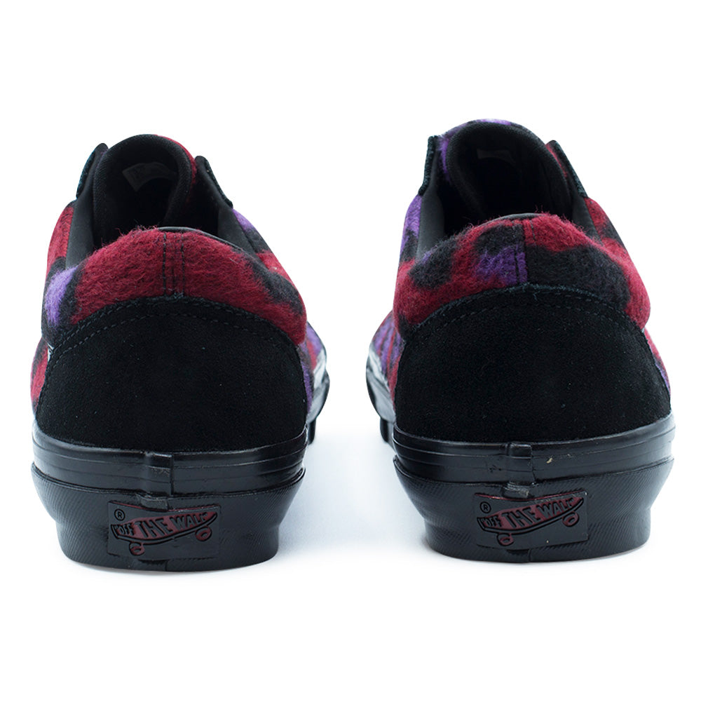 Rear studio perspective of the Vans LX Old Skool heels, displaying the seamless black suede heel caps topped with hairy red and purple fleece collars, tonal leather interior linings, and classic red-accented rubber "Vans Off The Wall" skateboard heel license plates mounted on glossy black midsoles.