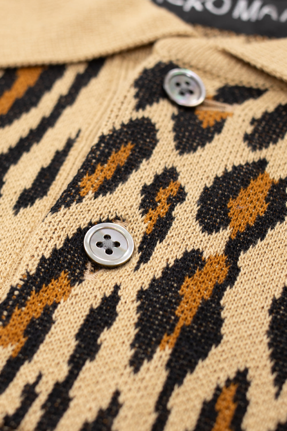 macro detail of Wacko Maria leopard knit polo shirt showing fine knitted cotton texture, natural mother-of-pearl buttons and premium Japanese garment craftsmanship