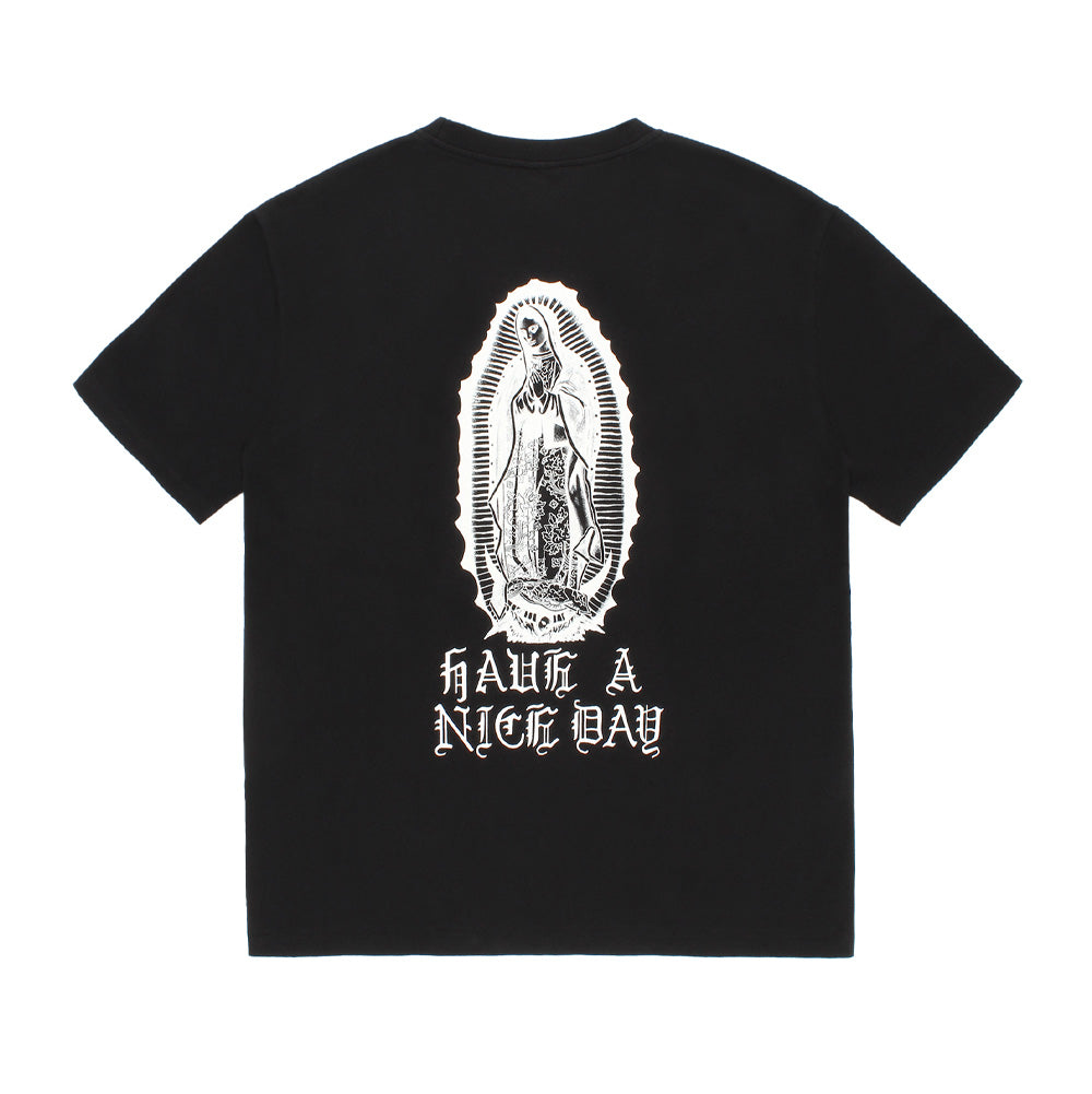 Back studio flat lay view of the Wacko Maria Washed Heavy Weight Crew Neck T-Shirt Type 4 in solid black, highlighting the boxy skate fit, ribbed collar, and centered white monochrome screen print of Our Lady of Guadalupe (Virgin Mary) standing in an aureole, underlined by arched gothic Old English typography reading "HAVE A NICE DAY".